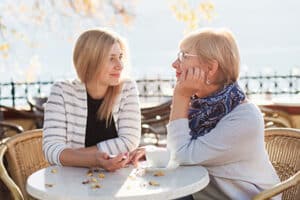 Woman meets with her birth mother in a street cafe outside