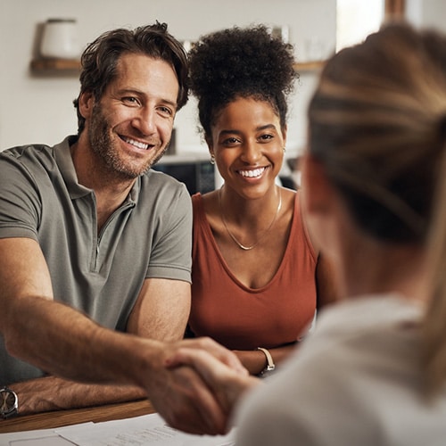 A home study social worker shakes hands with the husband during a home visit