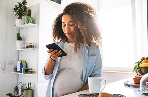 Pregnant woman looking at adoptive family websites from her kitchen