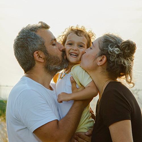 Hopeful adoptive parents kissing their biological child