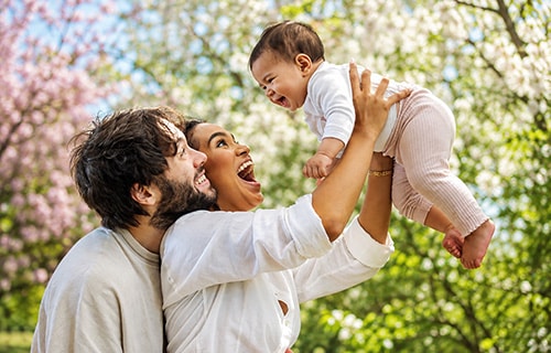 Joyous parents and their giggling infant daughter in a park