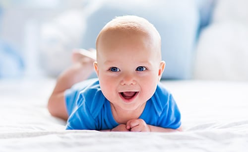 Happy baby boy in a sunny bedroom
